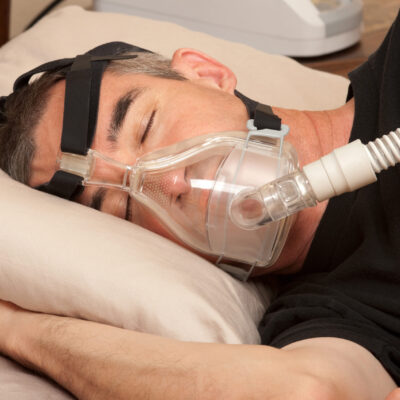 Sleep Apnea and CPAP Man with sleeping apnea and CPAP machine